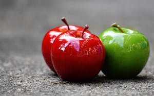 Three apple fruits are placed on a smooth surface.