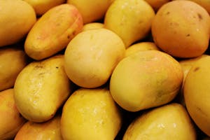 ripe yellow mango fruits with smooth skins, piled together.