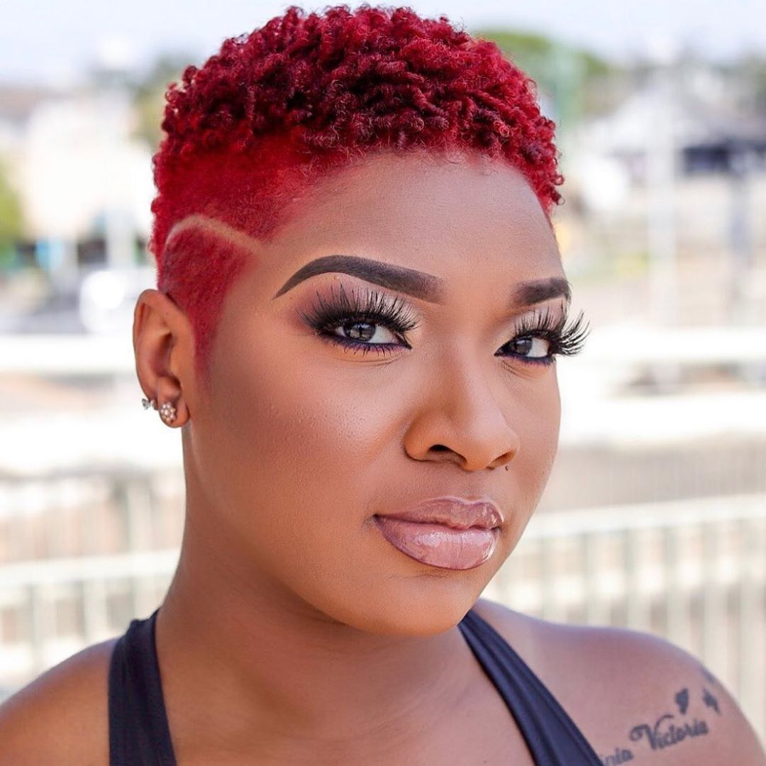 A brown-skinned lady in a cranberry crush colour hairstyle 