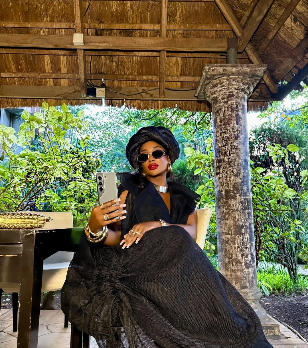Chioma Good Hair posing in a layered black outfit with a black turban