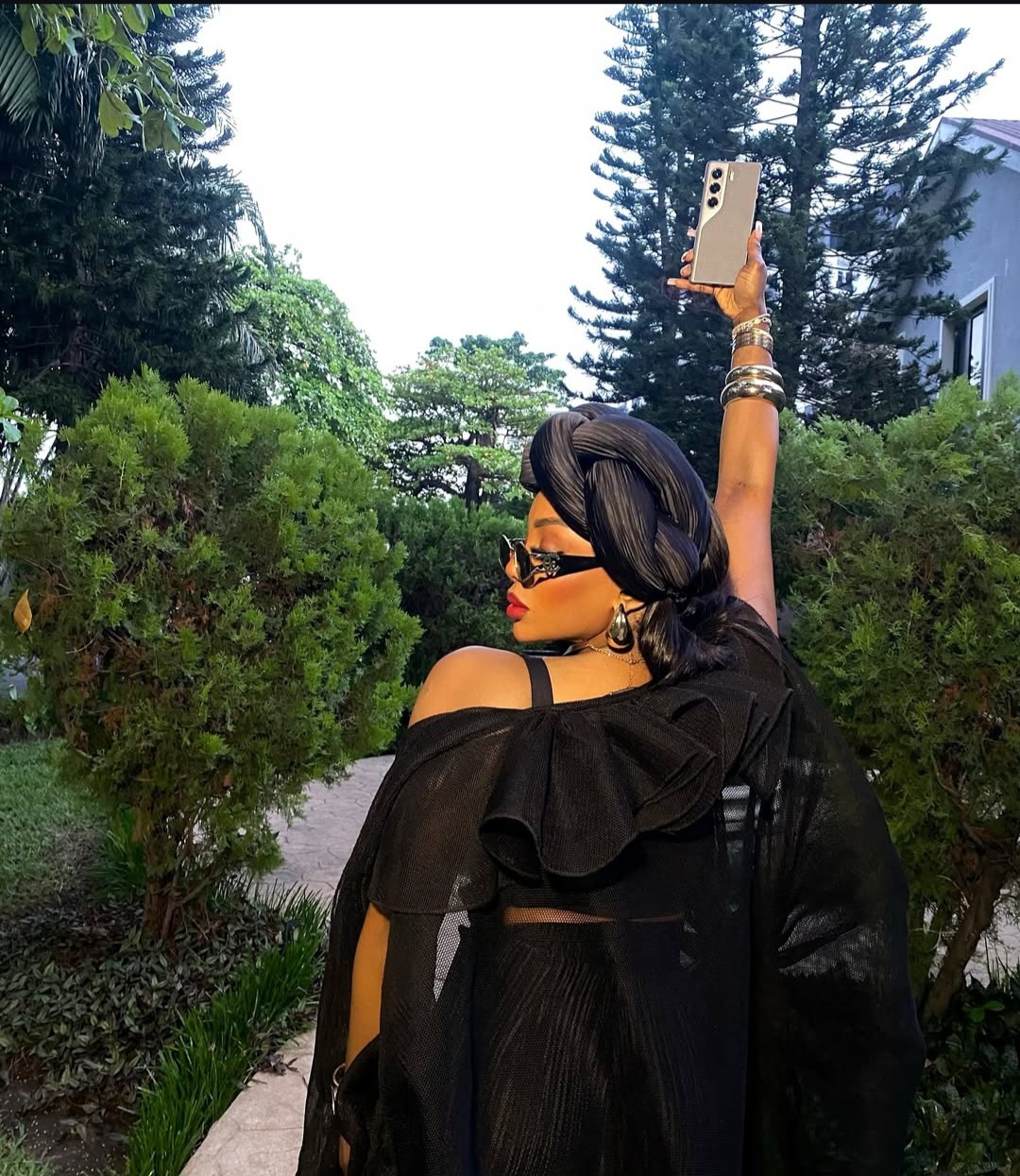 Chioma Good Hair posing in a layered black outfit with a black turban