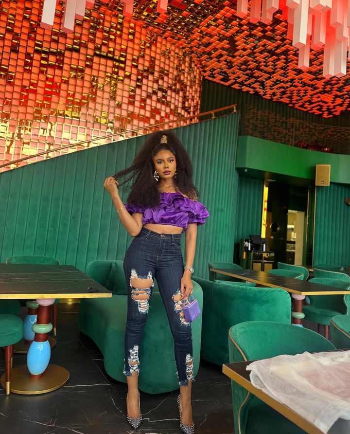 Nancy Isime in ripped jeans and a ruffled top